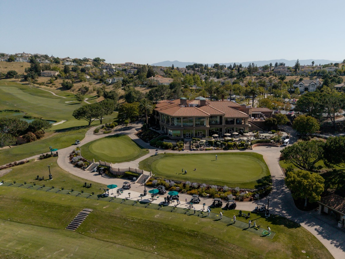 Aerial view of a clubhouse above the putting greens and driving range