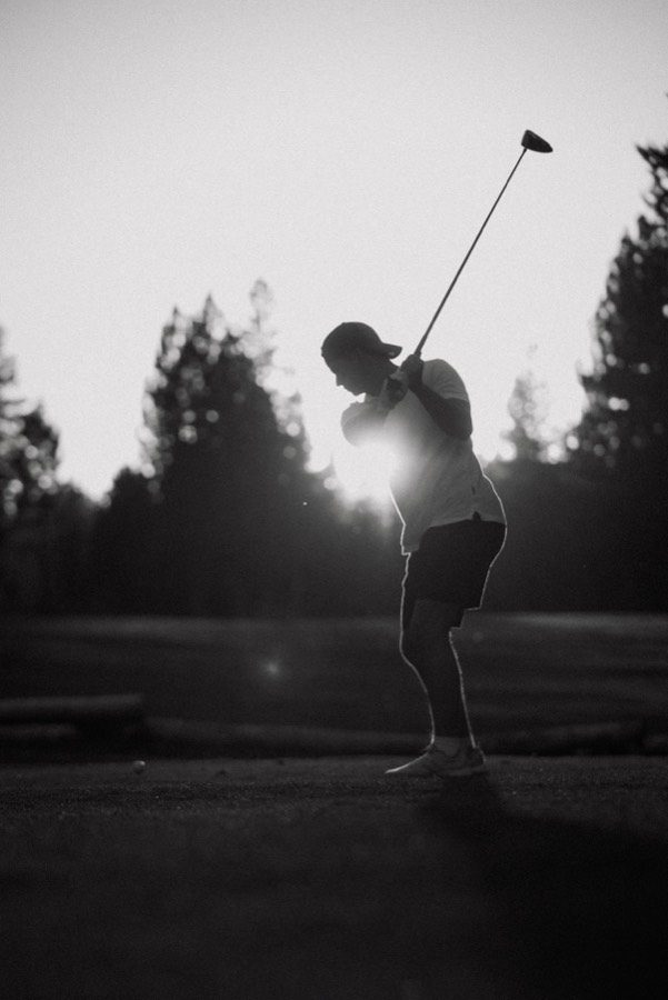 Black and white silhouette of a golfer against the sun