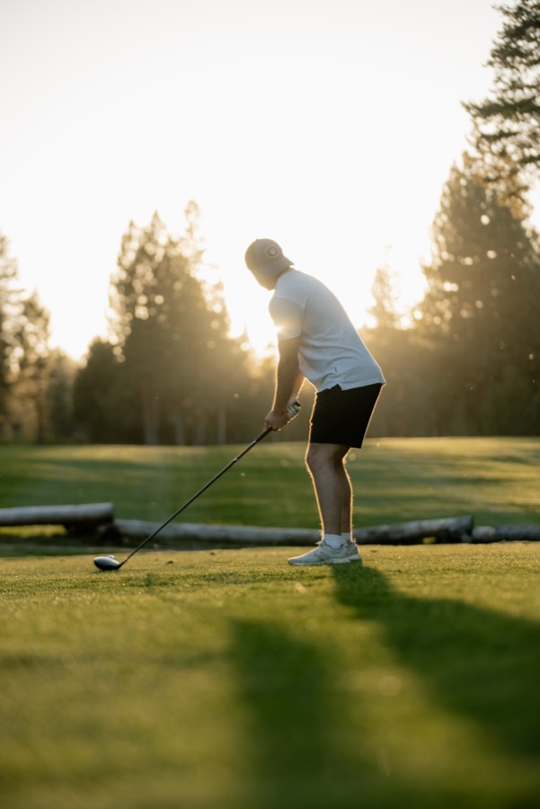 Golfer swinging at sunset